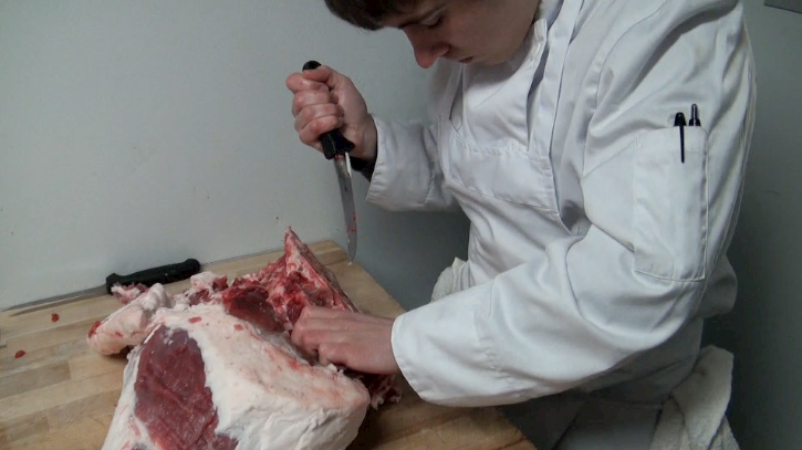 Stratford Chefs School Student Vince Stacey gets to work butchering a pig.