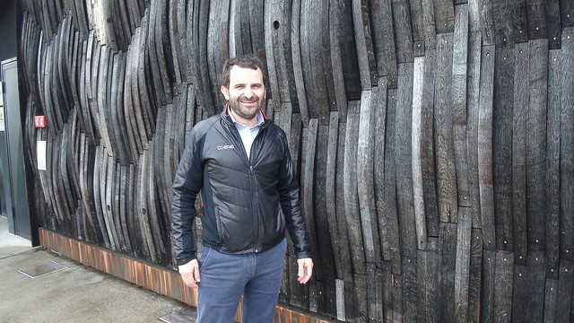 Achille Boroli in front of his winery where the walls are covered in old barrels
