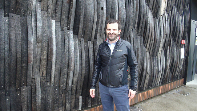 Achille Boroli in front of his winery where the walls are covered in old barrels
