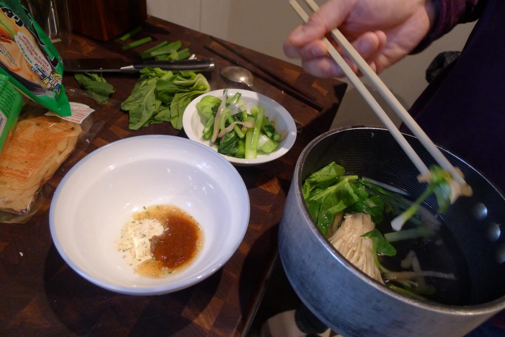 "Melting" the flavouring sachets and taking the greens and mushrooms from the broth pot.